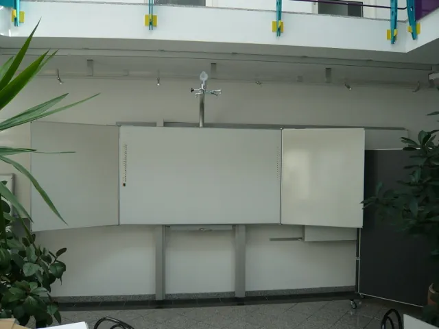 Whiteboard mit Seitenflügel und Beamerarm in einem hellen Lichthof